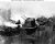 Ship's after 5'/38 twin gun mount burning, as her crew tried to control fires on 19 March 1945. The carrier had been hit by a Japanese air attack while operating off the coast of Japan. Photographed from USS Santa Fe (CL-60), which extinguished the fire in this gun mount by playing streams of water through the mount's open door. Later, the other 5'/38 twin gun mount and the 40mm quad machine gun mount (at right) also burned. Note ammunition loaded in the feed racks of the 40mm guns.